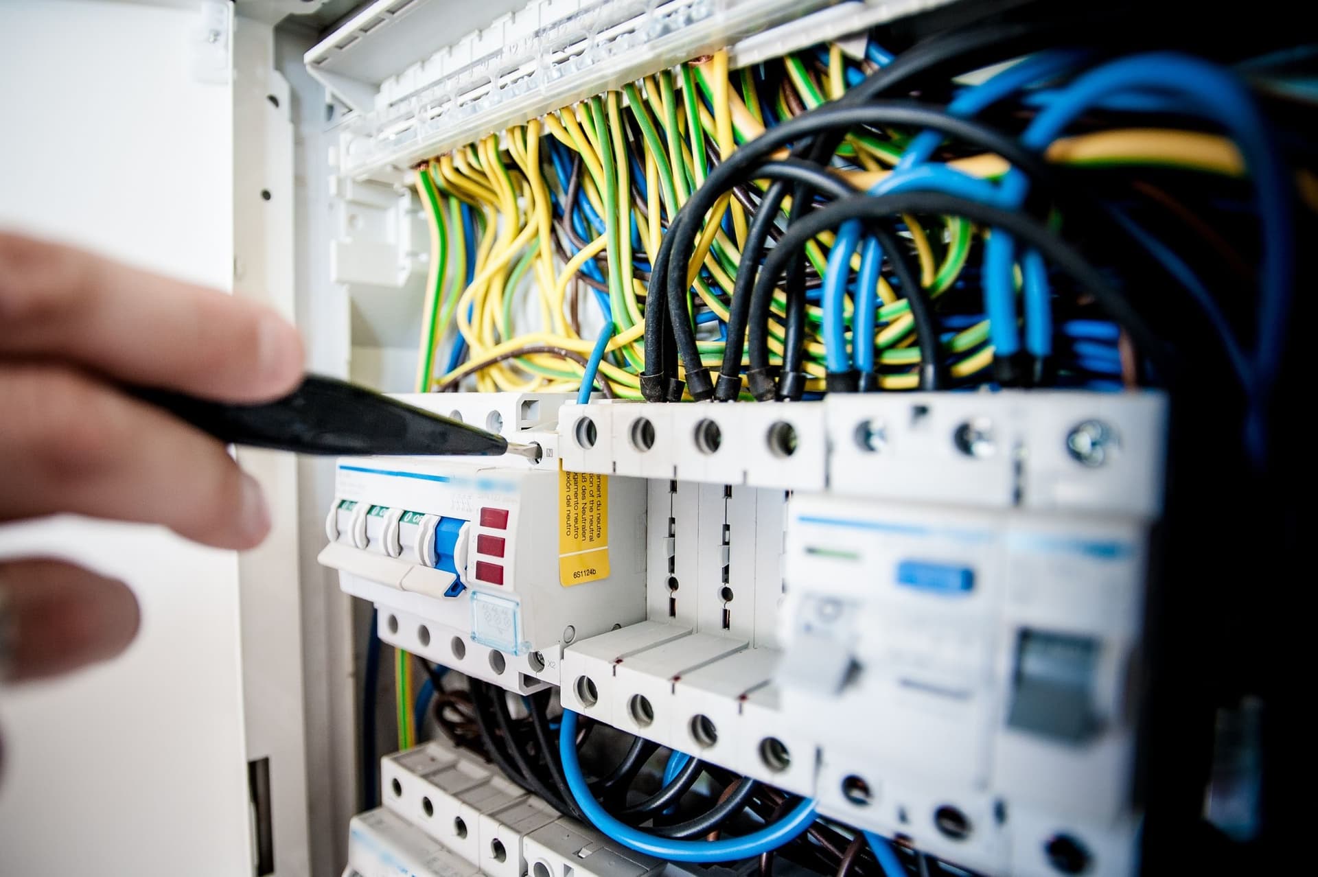 Hand testing a circuit breaker in a fuse box.