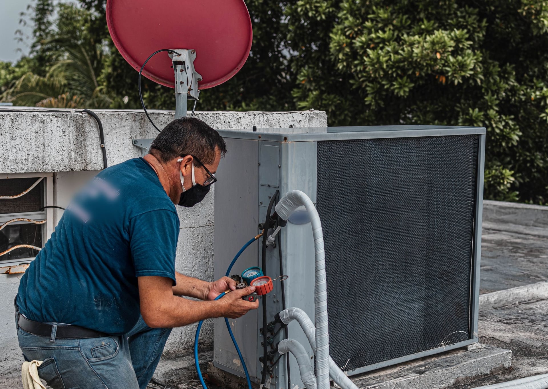 Technician checking an outdoor air conditioning unit with gauges.