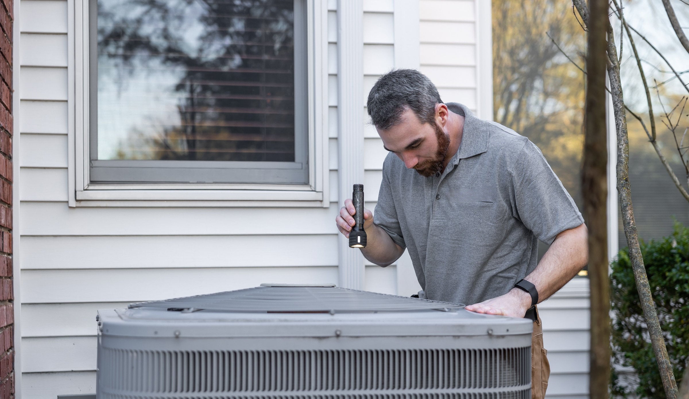 A technician inspects an outdoor HVAC unit for maintenance.