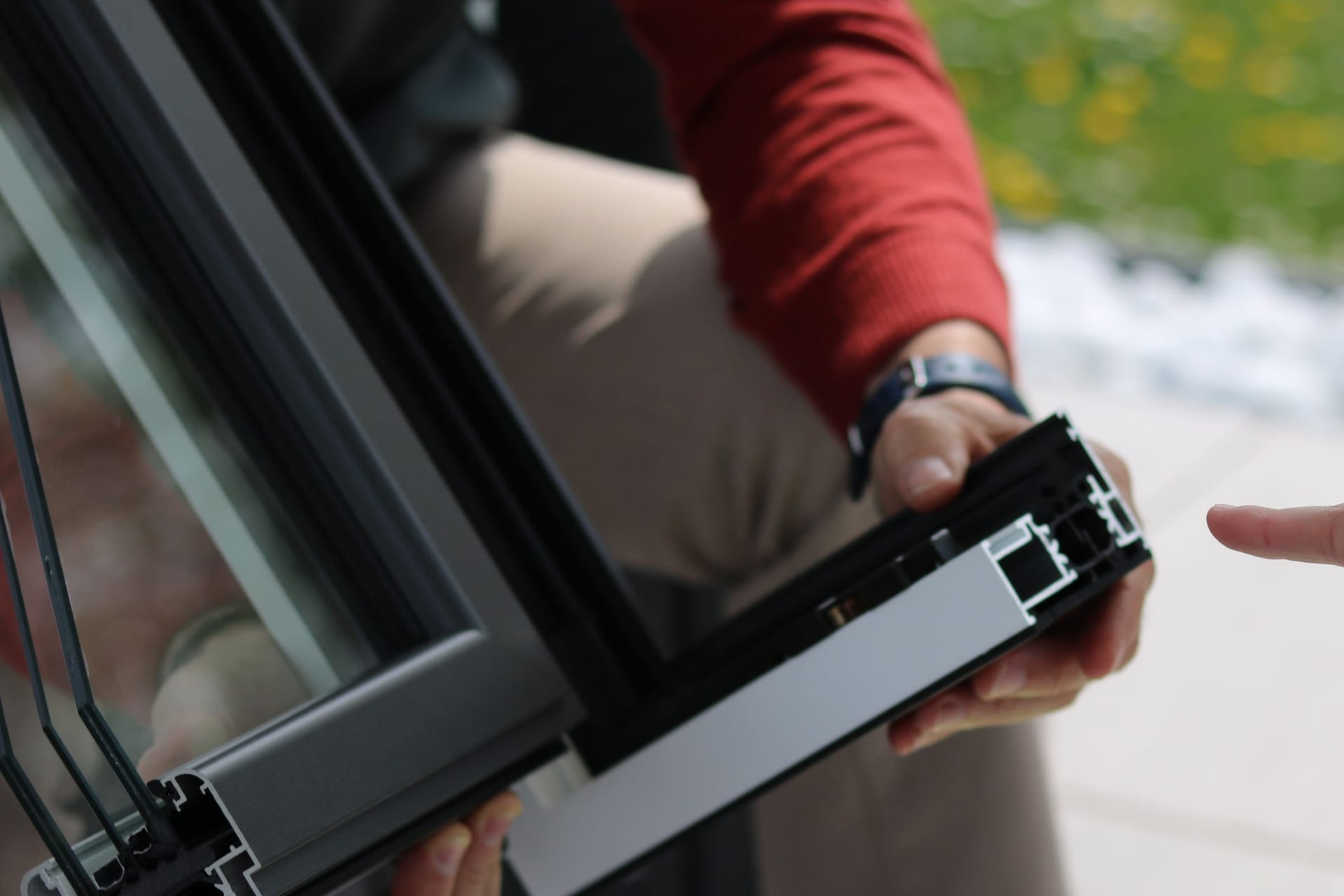 Person holding a cross-section of an aluminium window frame.