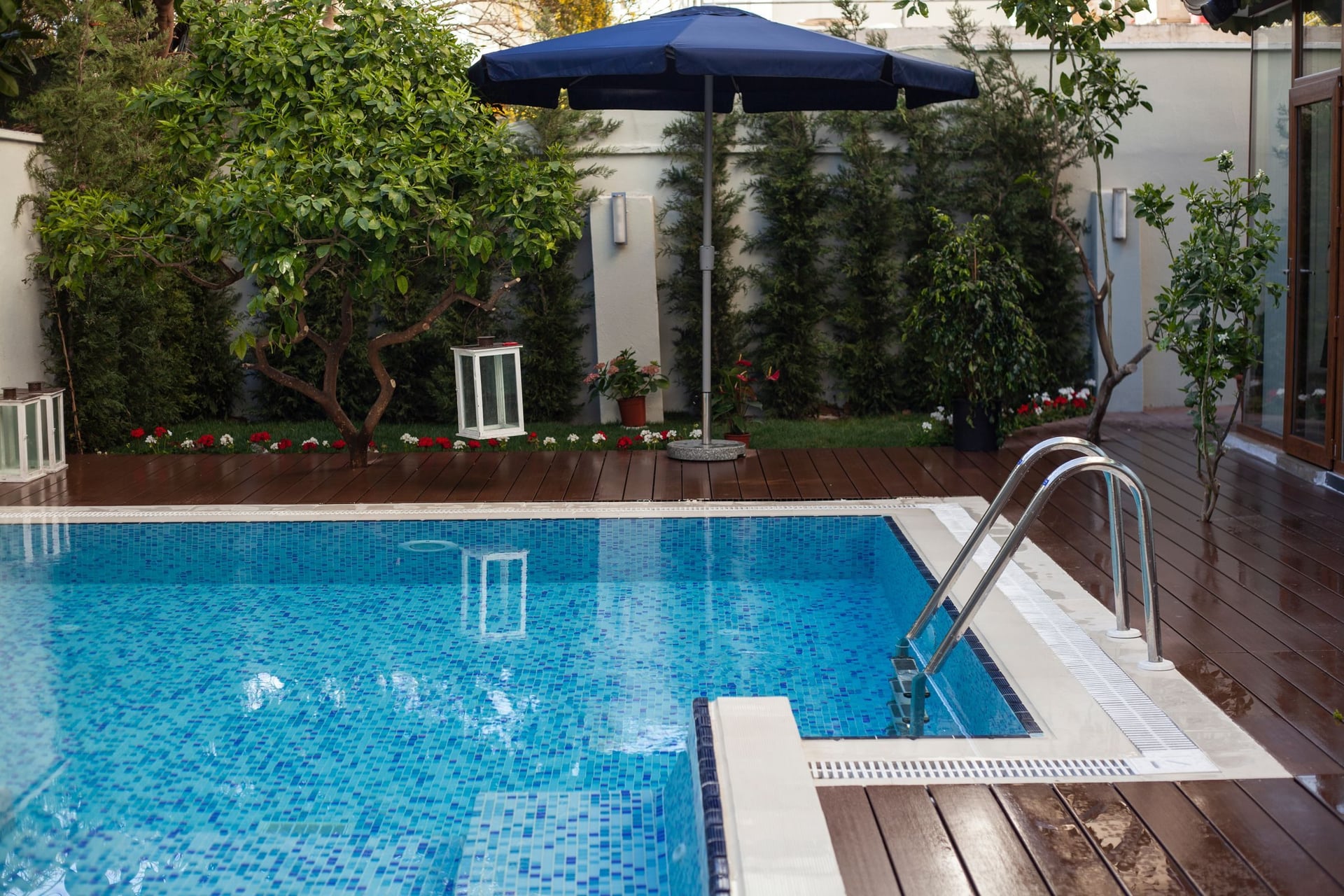 Backyard swimming pool with a wooden deck and garden.