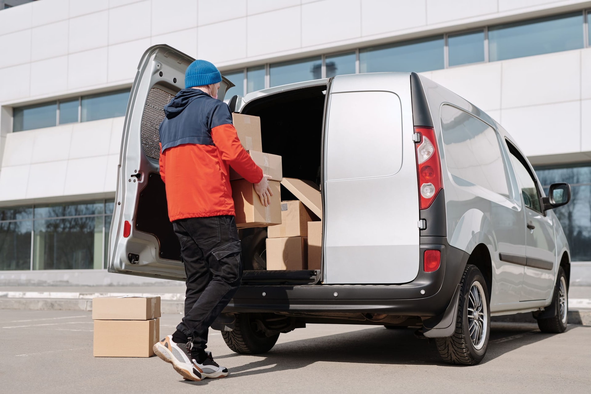 Person in a jacket stacking boxes in the back of a van.