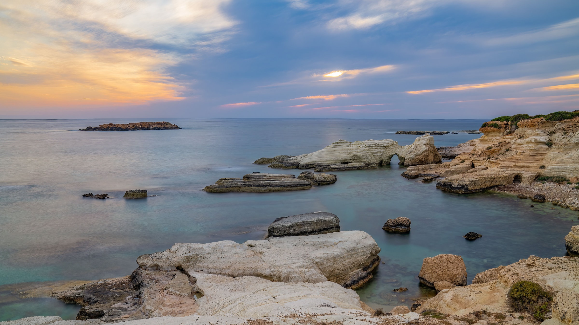 Peaceful sunset over a rocky coastline with ocean view in Cyprus. Ideal for travel and nature themes.