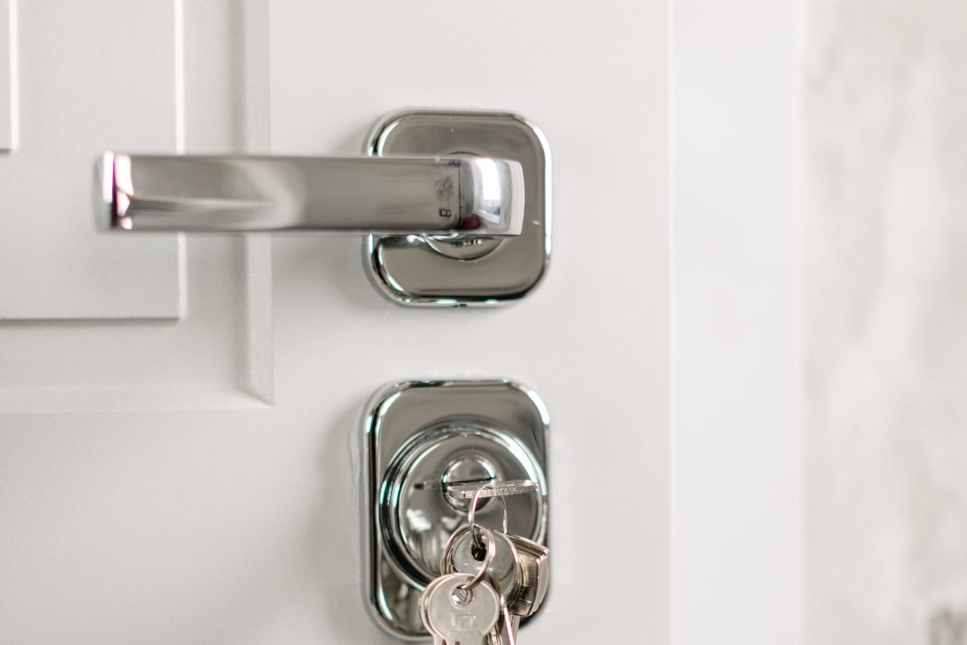 Keys hanging in the lock of a modern white front door.