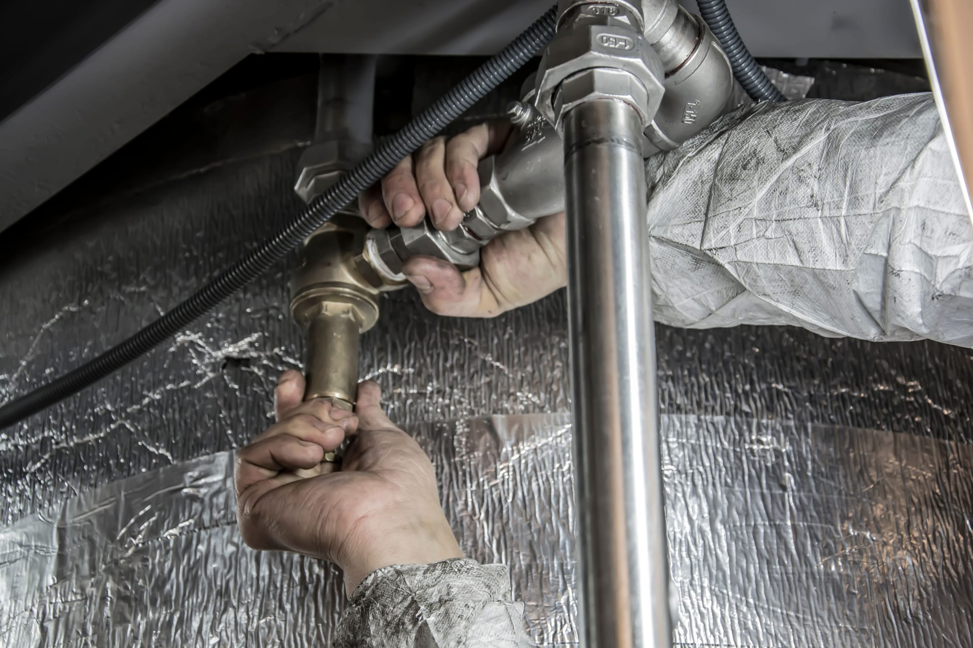 Hands tightening steel pipe fittings with a wrench.